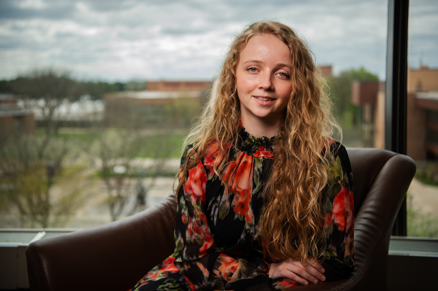 Young woman sitting in front of window overlooking college campus